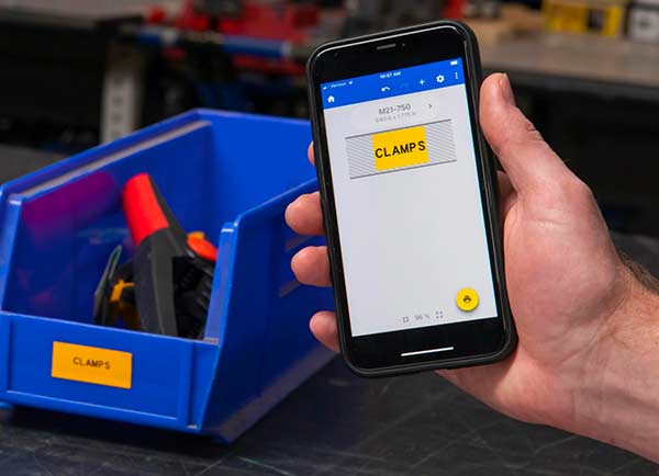 Un modèle d’étiquette sur un écran de l’application mobile Étiquettes express à côté de l’étiquette imprimée. Les deux sont en jaune vif et indiquent « CLAMPS ».