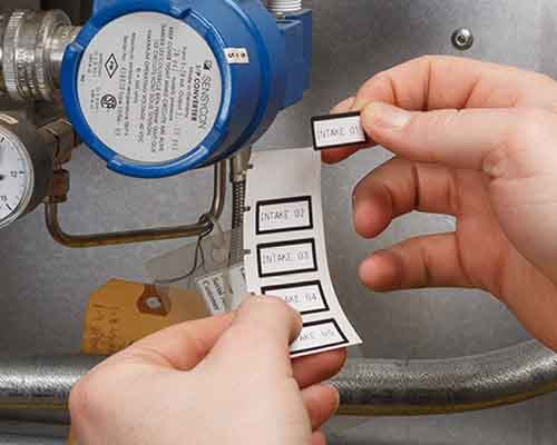 Une personne appliquant des étiquettes imprimées sur une M610 sur une machine.