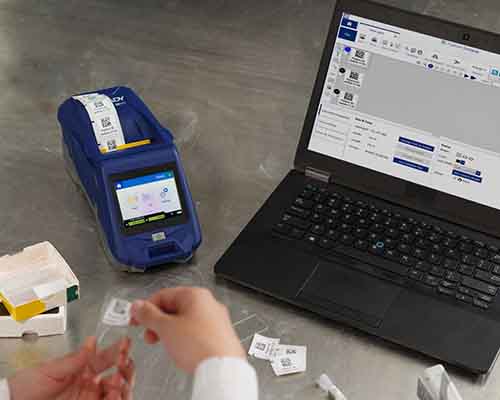 Une personne appliquant une étiquette imprimée sur une M611 sur une lamelle de laboratoire.