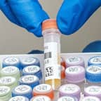 Un technicien de laboratoire tenant un tube à essai doté de deux étiquettes à code-barres.