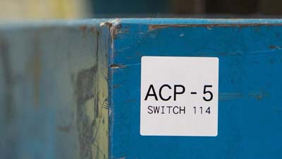 Une étiquette blanche, contenant du texte, appliquée sur un équipement. 