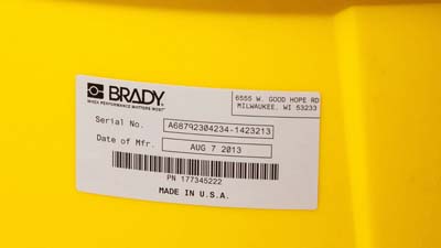 Une étiquette Brady en polyester métallisé brillant appliquée sur la surface incurvée d’une boîte plus grande.