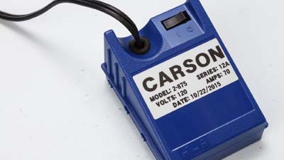 Une étiquette Brady métallisée à finition mate appliquée sur un appareil électrique, identifiant sa tension et son ampérage.