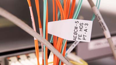 Une étiquette Brady QuickFlag fixée sur un câble, au milieu d’un groupe d’étiquettes, contenant un texte imprimé pour l’identifier.