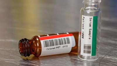 Deux flacons, l’un doté d’une étiquette en polyester rouge et l’autre d’une étiquette verte.