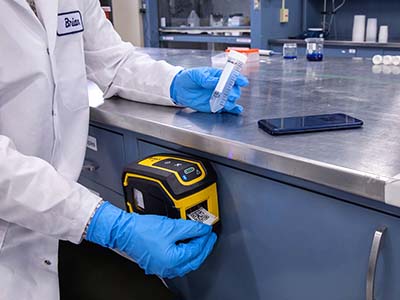 Une étiqueteuse M211 est idéalement fixée à un poste de travail de laboratoire.